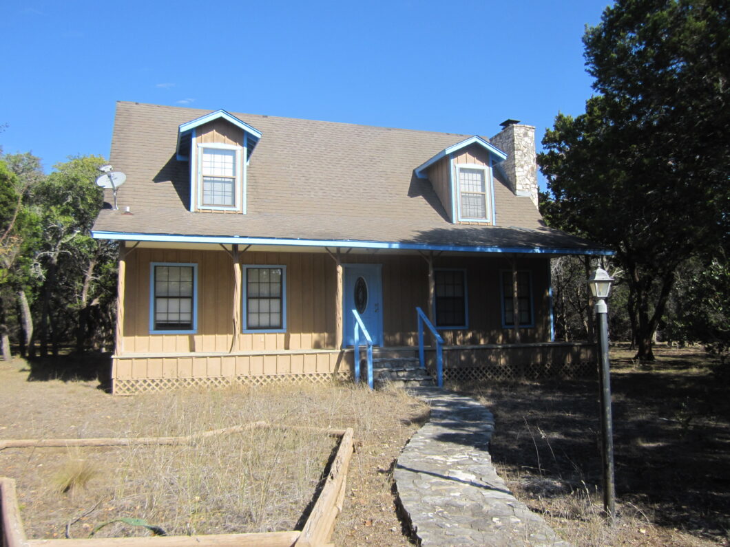 A house with blue trim and windows in the middle of nowhere.