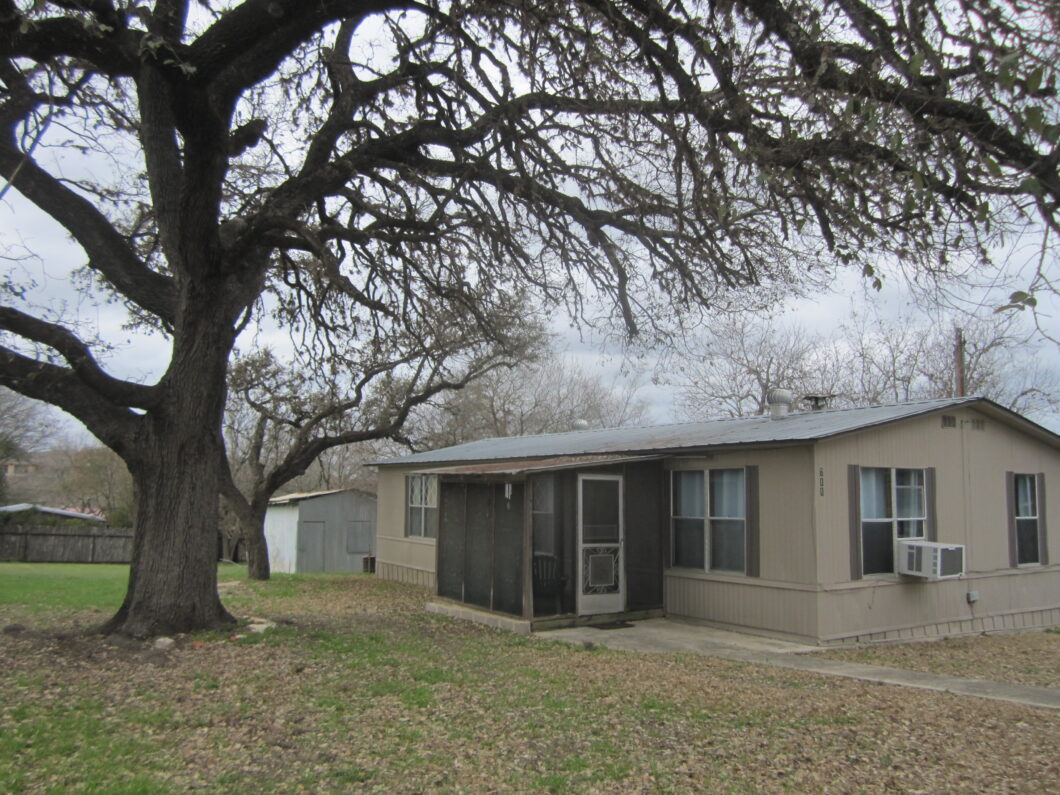 A house with a large tree in the background.